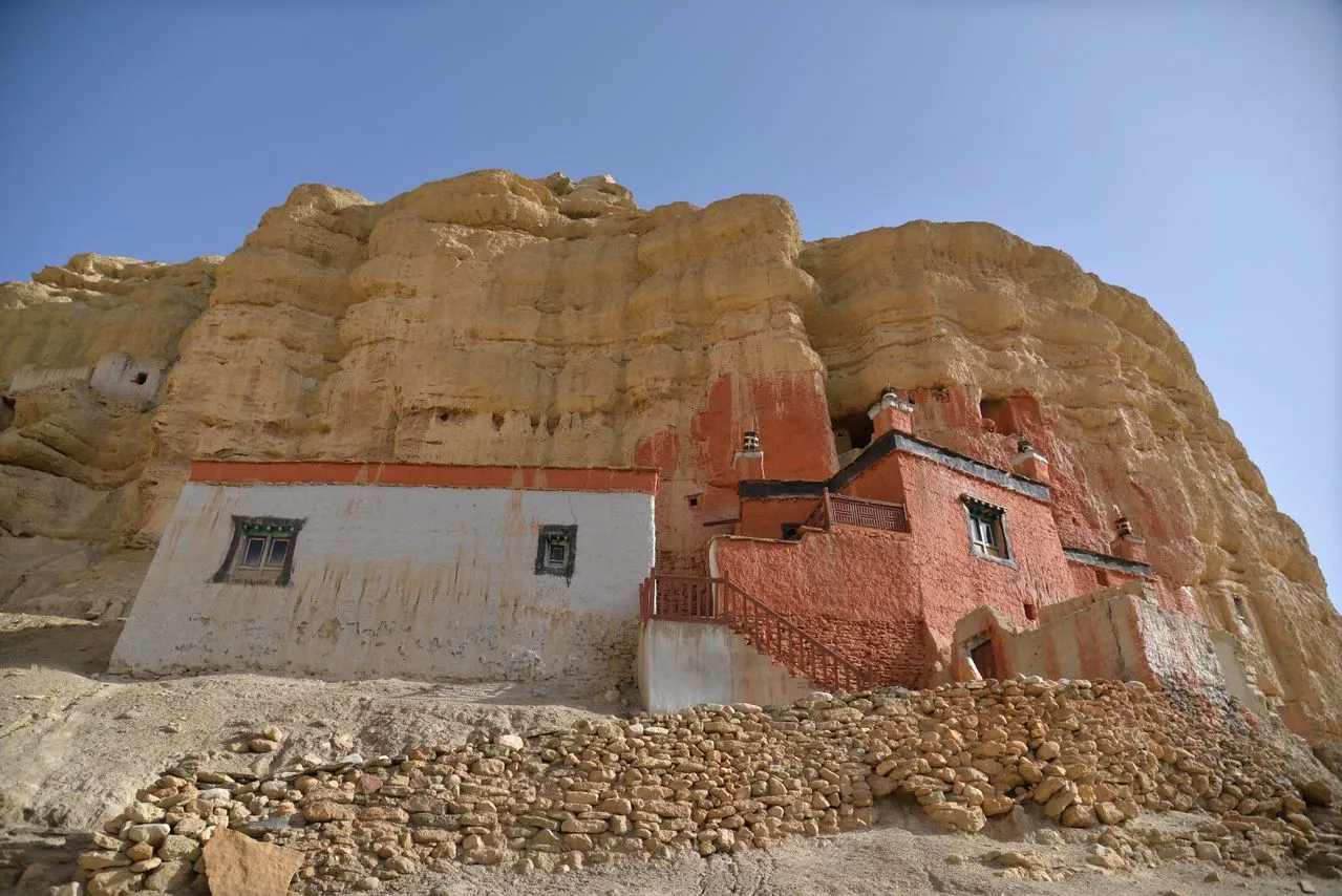 Niphu Monastery, an ancient Tibetan Buddhist cave monastery built directly into the towering, eroded clay cliffs of Chhoser in the Upper Mustang region of Nepal.