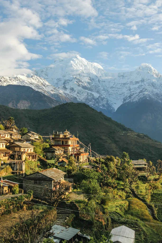 Nepalese mountain village with terraced fields under snowy Himalayan peaks.