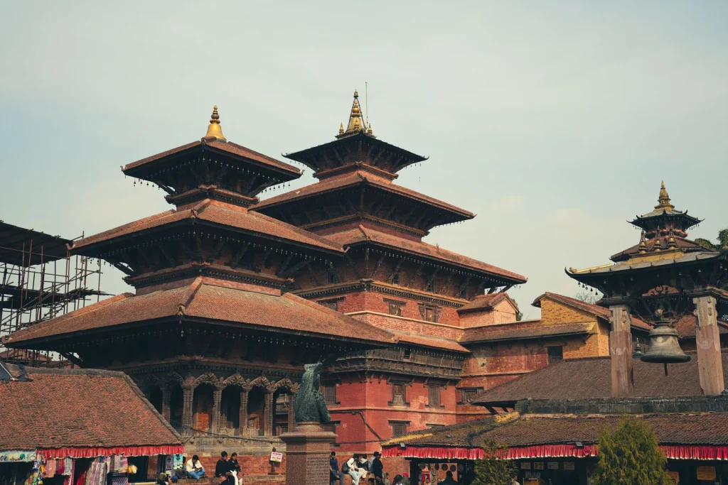 Traditional multi-tiered Newari temples with red brick walls and pagoda-style roofs in Patan Durbar Square, Nepal.