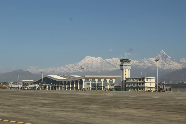 Pokhara International Airport terminal building and control tower in Nepal, set against the snow-capped Annapurna Himalayan mountain range.